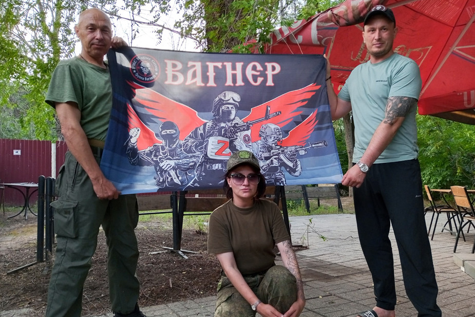 Екатерина Линтас (в центре) на фоне символики ЧВК «Вагнер»